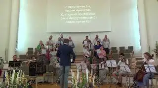 В сопровождении оркестра хор поёт гимн "Людям нужен Бог"