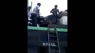 MAN CARRIES MOTOCYCLE ON HIS HEAD.
