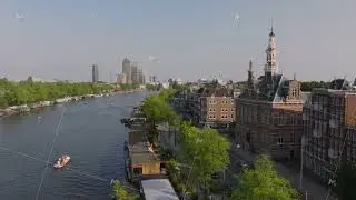 Amsterdam's canals with house boats docking and motorboats passing by historic and modern buildings