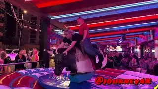 FUN GIRL AND GUY RIDING ON A BULL IN BENIDORM