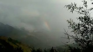 PELANGI MUNCUL DI SELA GUNUNG DISELIMUTI DENGAN KABUT