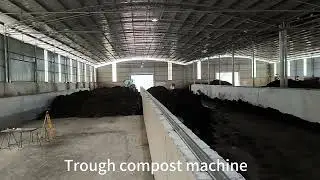 Motor-driven trough compost turner for commercial composting in an organic fertilizer plant.