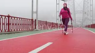 Nordic walking. Young chubby Caucasian woman hiking with the Nordic poles. Static shot slow moti...