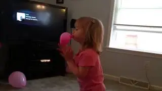 Evie blowing up a balloon.