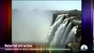 Tourists take dip in pool atop 250 foot waterfall.