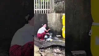 Filipina washing many dishes at well , only water in Tagbobo