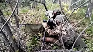 Снайпер и его помощник работают в маскировке в лесу. 