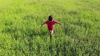 young woman in red sexy dress walking by green field, raise up hands, happy inspirational freedom