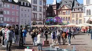 Street performer blowing bubbles by St Peter's Fountain in Trier, Deutschland  (Germany) town square