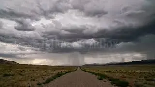 8K Stock Video - Timelapse of rainstorm looking down dirt road of into the desert landscape