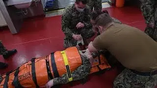 U.S. Sailors practice using a Reeves sleeve stretcher