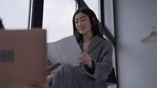 portrait of intelligent smart asian young woman in headphones and bathrobe reading HD