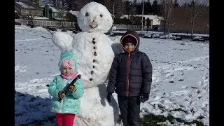 Настя и Никита лепят снеговика. Дети играют в снежки и смеются.