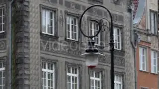 an Old Fashined Lamppost Standing Near a Xix Century European Building With Heavy Snow Falling