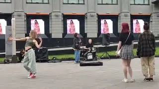 Девушка в мокрых кроссах горячо танцует напротив ЦУМа под песню уличных музыкантов.