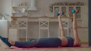 Determined motivated attractive sporty fit mature female practicing weight training, performing dumb