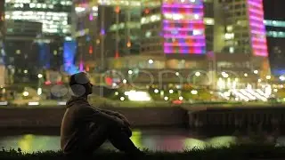 The Dreaming Young Man And Sky-Scrapers Background At Night, Time Lapse. Stock Footage