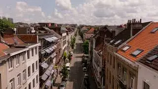 Camera gliding forward over a lively city street in Europe. Parked and moving cars on a sunny summer