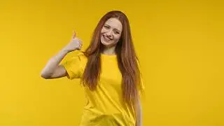 Positive sunny woman makes hand sign like, thumbs up gesture  Happy lady in yellow outfit, correct p