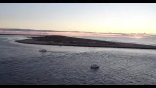 Aerial tracking shot of inlet from ocean to bay at sunrise