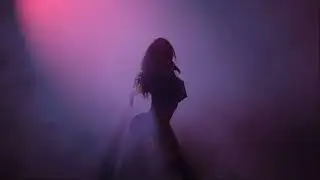 Synthwave. Cyberpunk. Electric. Dancing.Young woman dancing under a cloud of smoke.