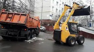 Даня смотрит, как трактор убирает снег в Камаз.