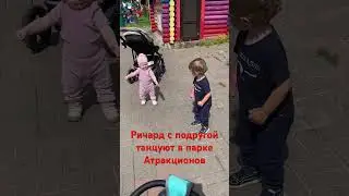 Малыши танцуют в парке аттракционов