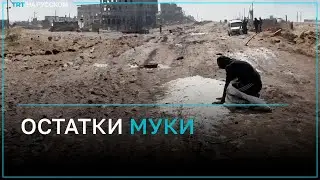 Палестинец пытается собрать остатки рассыпанной на земле муки