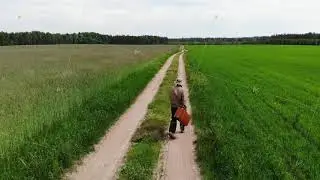 Lonely lost and disappointed man walking alone in despair with suitcase by country road in a green