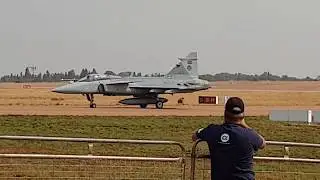 Two Saab JAS 39 Gripens taxiing across a military runway to take off