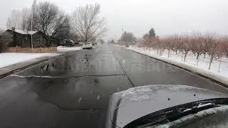 Stock Video - Slow motion of snow falling while car drives down street