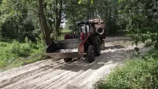 Трактор едет по песку с прицепом
