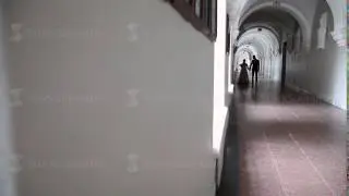 Bride stands before groom in white corridor inside