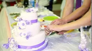 A bride and a groom is cutting their wedding cake