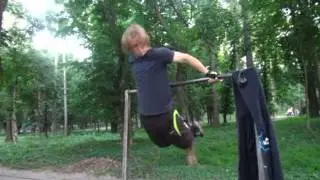 Парень занимается на турниках в парке.Смотри