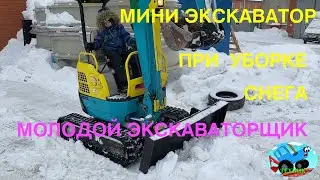 Мини экскаватор и молодой тракторист на уборке снега. Лёгкий в управлении, справляется даже ребёнок.
