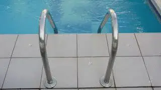 Shiny stainless steel ladder descending into crystal blue pool