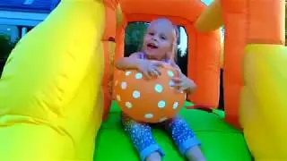 Alisa plays with balloons on the INFLATABLE slide plays