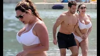 Kelly Brook's white bikini barely contains ample assets as she splashes in surf with Jeremy Parisi -