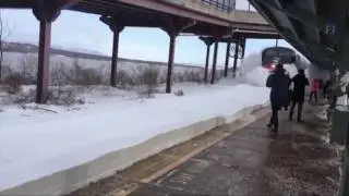 Поезд сносит снег на рельсах возле станции
