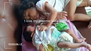2 years old sister kissing her preemie baby brother