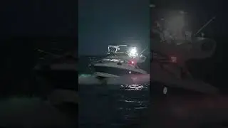 Blue yacht passing the Haulover Inlet Jetty after dark