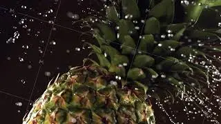 Super slow motion water drips on rotating Pineapple. On a black background.