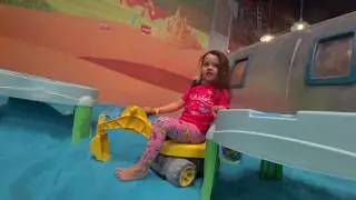 Настя и Катя играют в песочнице с ярким песком.