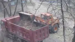 грейдер грузит листья в грузовик grader ship leaves in the truck