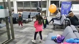 Niños juegan con globo naranjo en aeropuerto