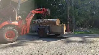 BX 25 unloading a utility trailer of firewood Alder logs.