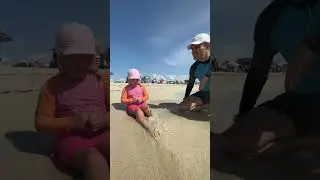 Малышка сидит, а её папа засыпает песком её ножки. Какой ваш любимый пляжный вид спорта или игра?