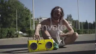 Exhausted Young Sportsman Wiping Face with White Towel, Turning Off Retro Tape Recorder, and Smi...