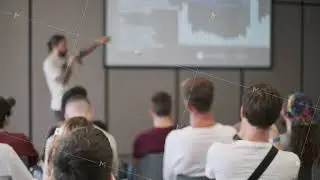 Audience listening to speaker presenting data on screen in conference room